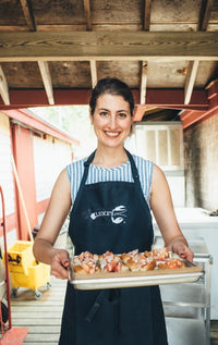 Lauren Gibson; woman in a Luke's apron, smiling, with a tray of lobster rolls