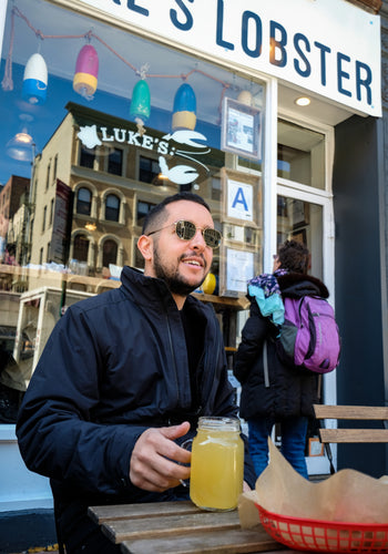 A man wearing sunglasses holding a beer outside of a Luke's Lobster shack