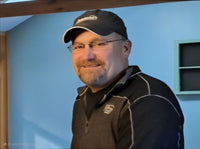 James wearing glasses and a baseball hat smiling for a photo