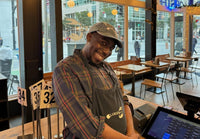 Johnnie Brown smiling while wearing a Luke's hat and apron at the shack