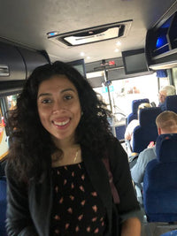 Klaudia Ramos; woman standing in a bus aisle, smiling