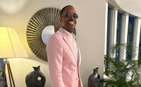 Willie Wilson; posing in a light pink suit while wearing sunglasses and smiling