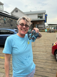 Tracey Price; holding a blue lobster while smiling