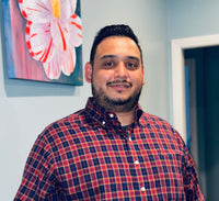 Armando wearing a red and blue checkered shirt posing for a picture