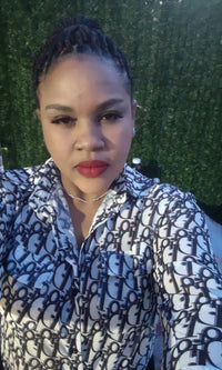 Nadia Gaston; taking a selfie in a white and black patterned button down shirt