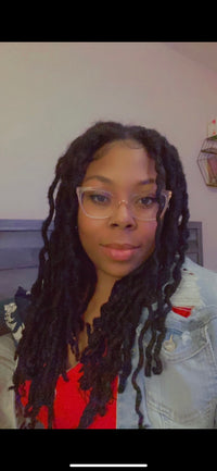 Mickelia taking a selfie while wearing glasses, a red shirt, and a jean jacket