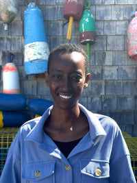 A woman smiling against a buoy wall