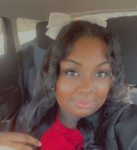 Kayla green wearing a black jacket and a red shirt smiling in the car while taking a selfie