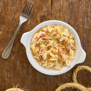 Load image into Gallery viewer, Lobster mac and cheese in a white dish on a wooden table
