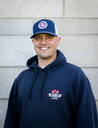 Brett smiling while wearing a navy hat and sweatshirt