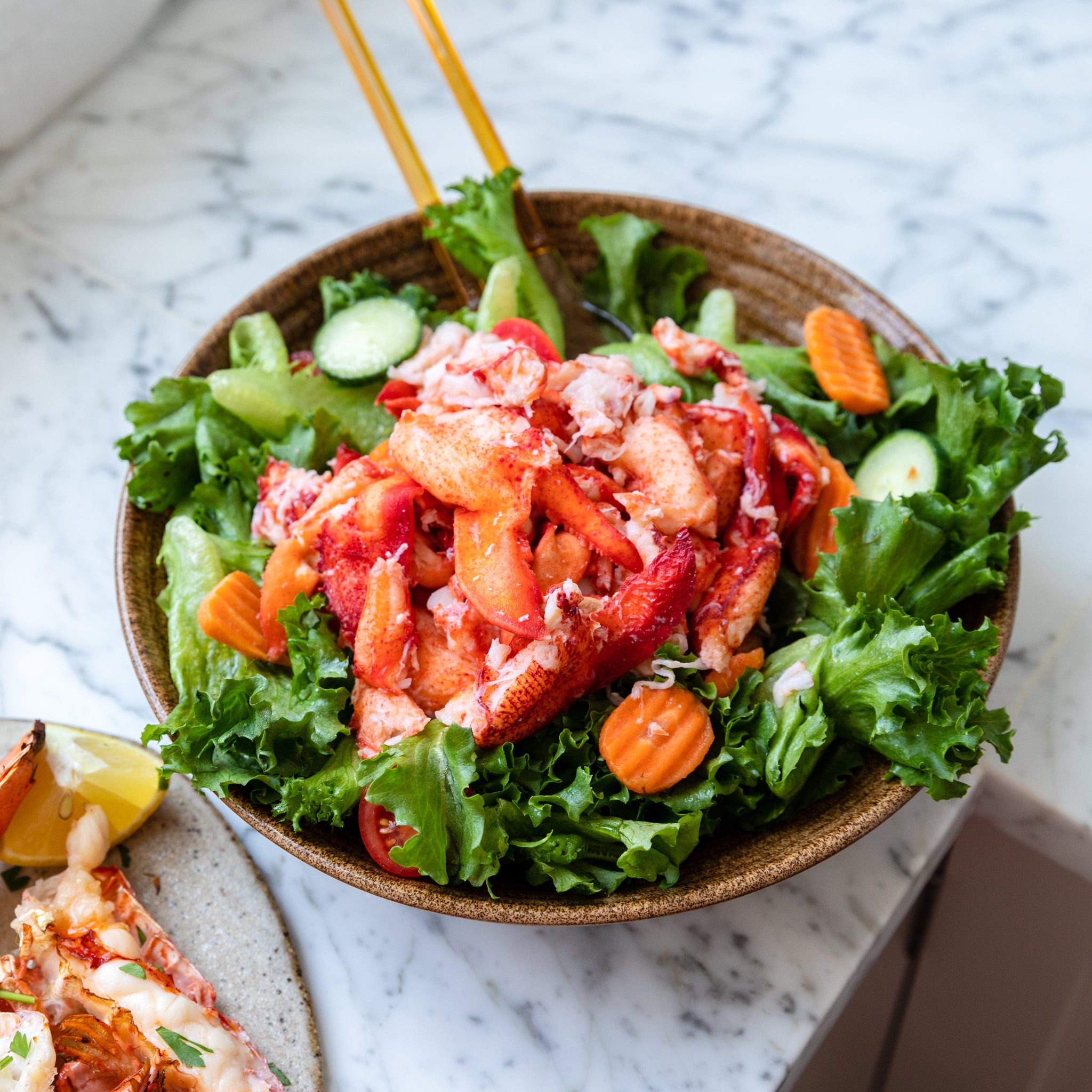Load image into Gallery viewer, Lobster meat on top of salad in a bowl o na marble countertop
