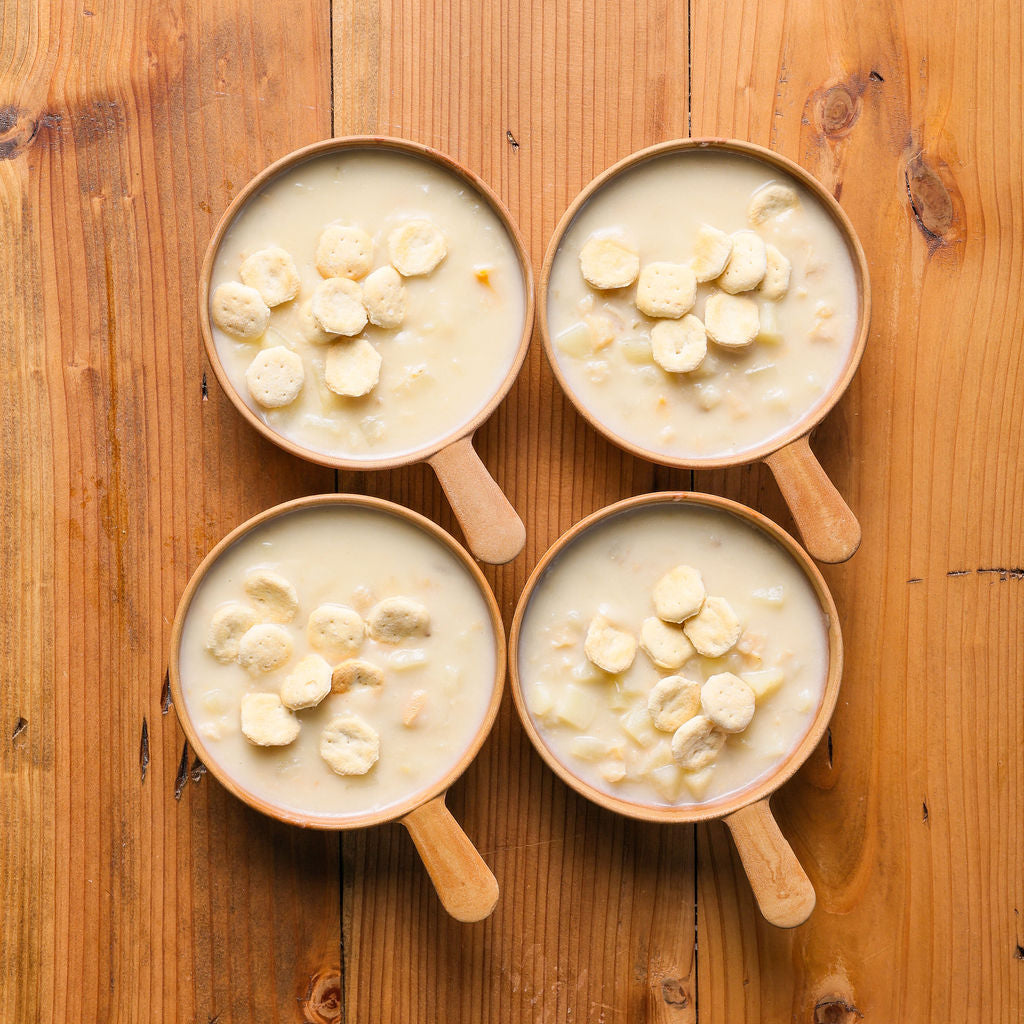Four cups of clam chowder in wooden bowls on a table