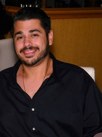 Luis wearing a black button down shirt smiling for a picture