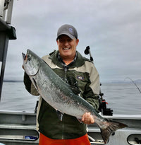 Kevin smiling for a picture while holding a fish on a boat