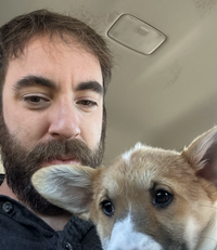 Kyle posing for a selfie with a corgi puppy