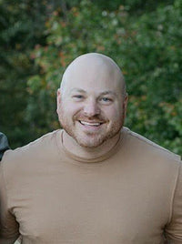 Tyler wearing a tan tee, smiling for a picture outside