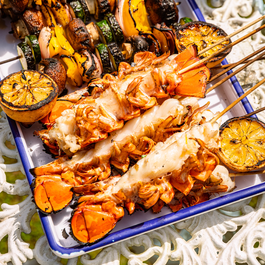Load image into Gallery viewer, split lobster tails and lemon and veg skewers on platter
