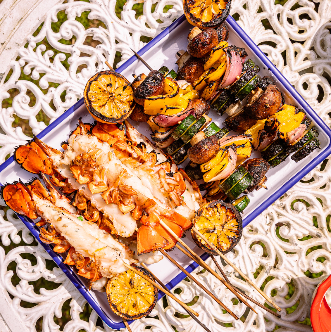 Load image into Gallery viewer, split lobster tail and veg skewers on platter

